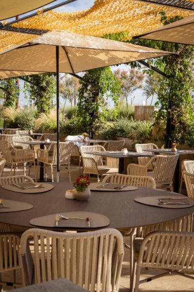 Terraza exterior del restaurante Savoia Hotel Rimini con mesas elegantes, sombrillas y vegetación
