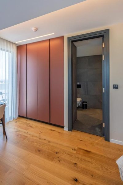 Armario empotrado en tono terracota y acceso al baño en suite del hotel Sky Suites Nicosia
