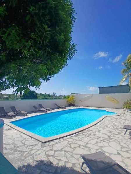 Piscina exterior con tumbonas y terraza de piedra en Ti Village Creole rodeada de vegetación tropical