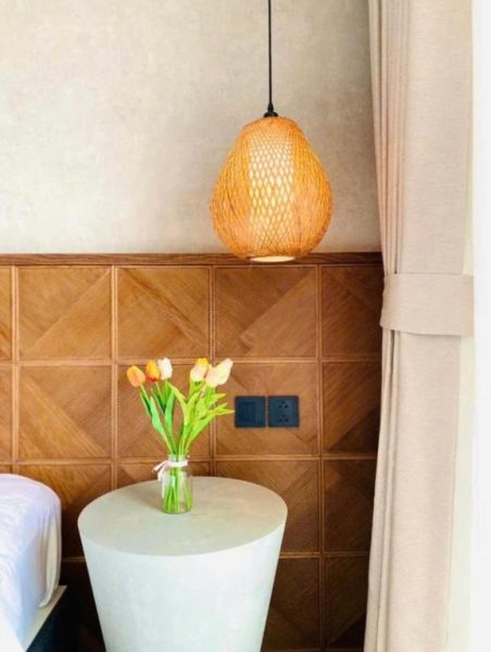 Mesita de noche con tulipanes y lámpara de mimbre en habitación del Panorama Beach Win Nha Trang