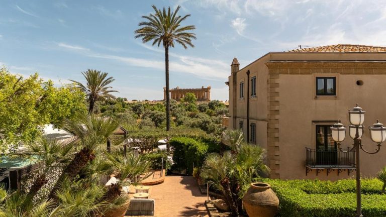 Jardín mediterráneo con palmeras y vista al Templo de la Concordia en Villa Athena Resort Agrigento