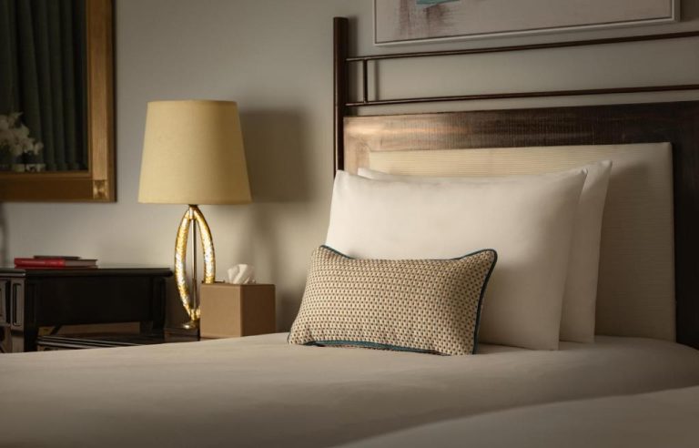 Habitación elegante con cama doble y lámpara dorada en el Corinthia St George's Bay