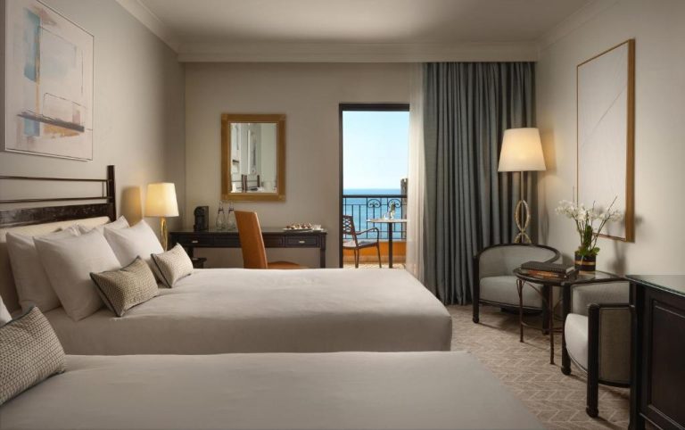 Habitación doble con dos camas y balcón con vistas al mar en el Corinthia St George's Bay