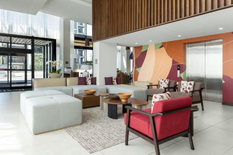 Lobby moderno con sofás blancos y sillones rojos en Residence Inn by Marriott San Jose Alajuela El Coyol
