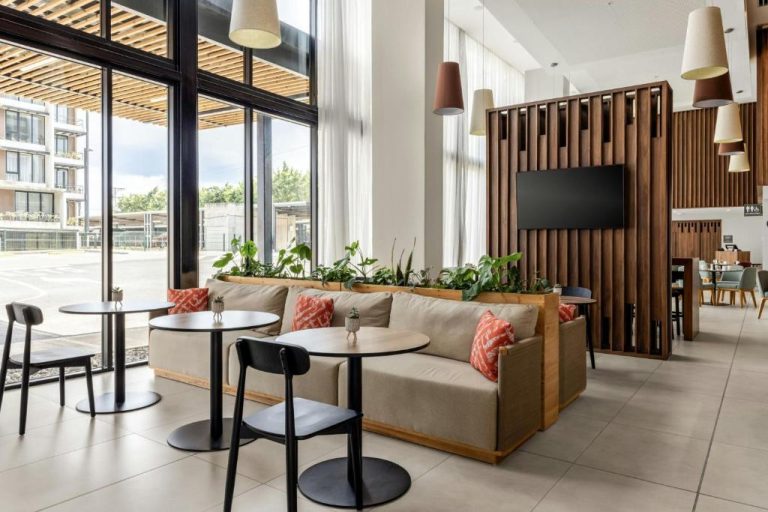 Zona lounge del Residence Inn by Marriott San Jose Alajuela El Coyol con sofás, mesas y plantas naturales