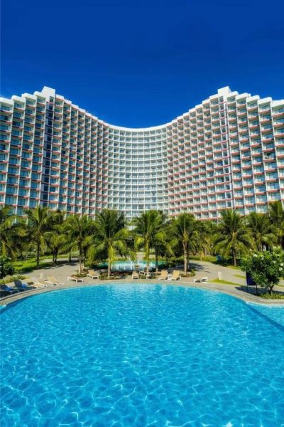 Gran piscina exterior con palmeras y vista al edificio principal del Hanna Seaview Stella The Arena Resort