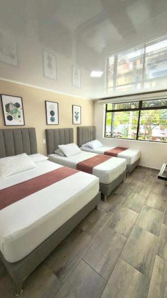 Habitación triple con tres camas individuales y suelos de madera en Hotel Nakama