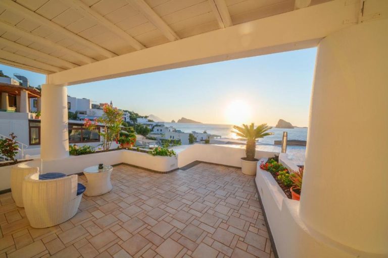 Terraza con vistas al mar y atardecer desde el Hotel La Terrazza con plantas y zona de descanso