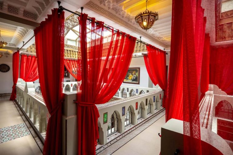 Patio interior con cortinas rojas y arcos árabes del Hotel Ryad Art Place Marrakech