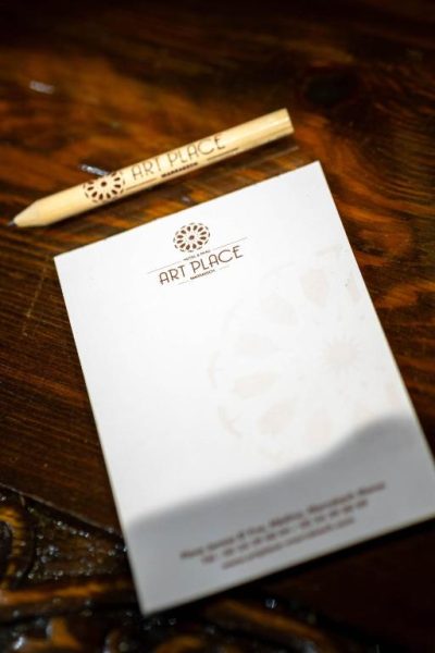 Bloc de notas y lápiz personalizados del Hotel & Ryad Art Place Marrakech sobre mesa de madera