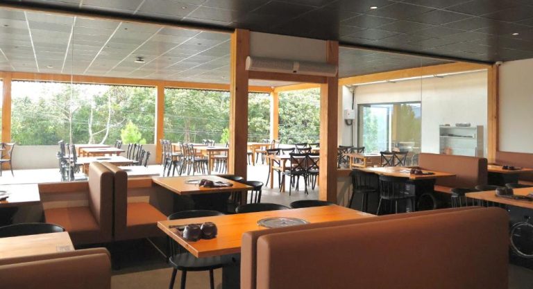 Restaurante interior del Chimney Hotel con mesas de madera, sofás y vistas al jardín