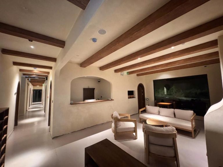 Lobby interior del Chimney Hotel Măng Đen con vigas de madera, sofás blancos y largo pasillo iluminado