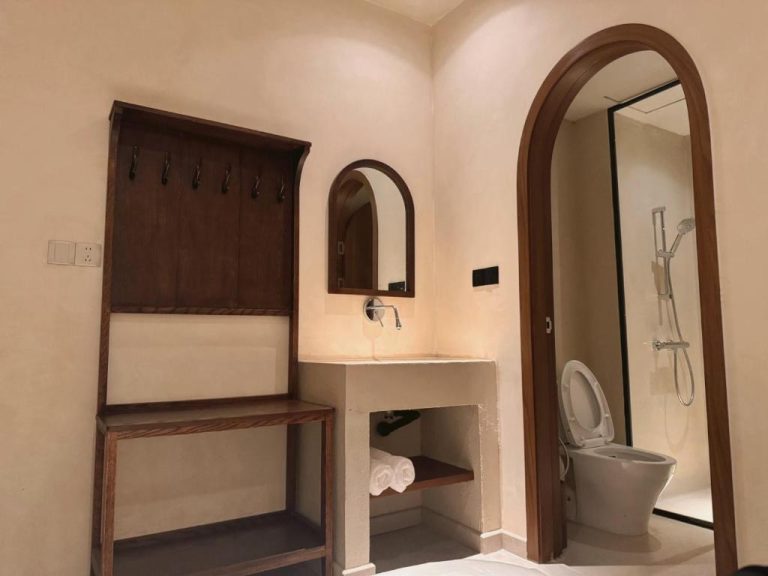 Baño moderno con ducha, lavabo de cemento y espejo arqueado en Ống Khói Măng Đen Chimney Hotel