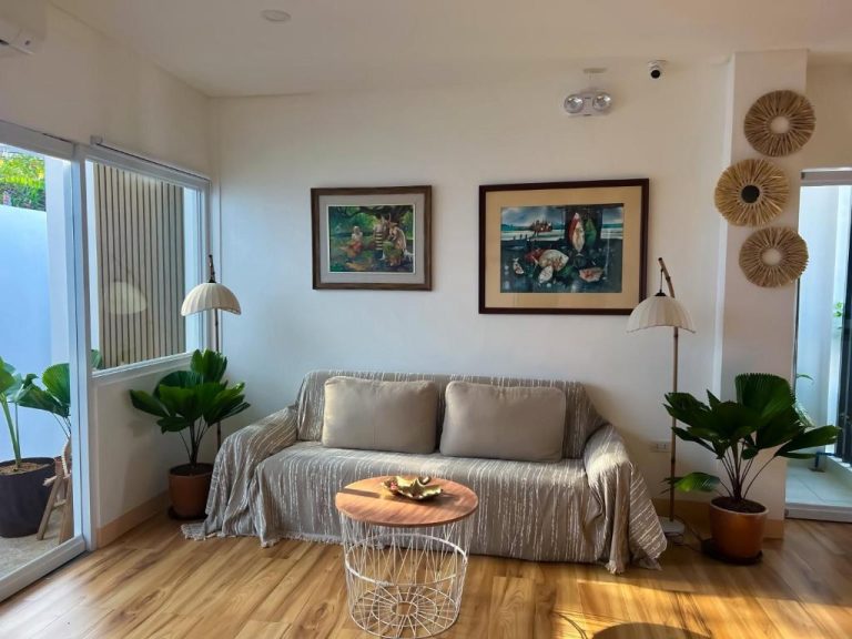 Sala de estar con sofá, plantas tropicales y arte local en Yuhum Boracay Suites