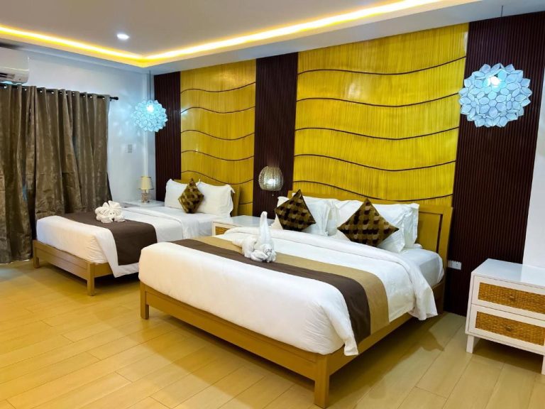 Habitación triple de lujo con dos camas king size y decoración tropical en Yuhum Boracay Suites