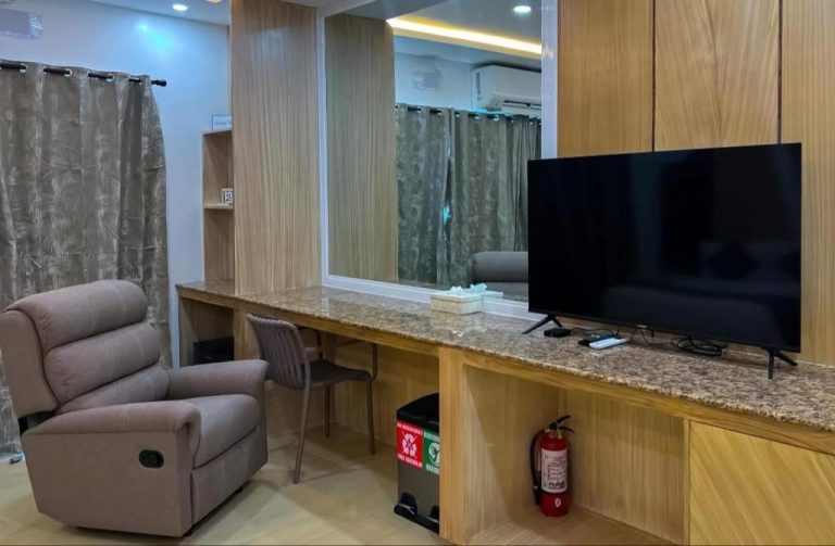 Sala de estar con televisor, sillón reclinable y escritorio en Yuhum Boracay Suites