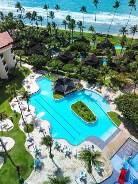 Vista aérea de la piscina exterior del Porto Beach Resort Marulhos Prime con palmeras y playa al fondo