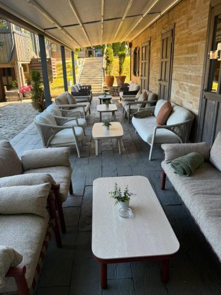 Terraza lounge exterior con sofás y mesas del Lakeside Hotel Plitvice rodeada de naturaleza