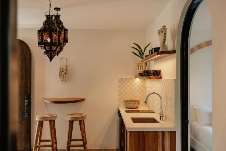 Cocina bohemia con lámpara marroquí y taburetes de madera en Domo Nosara Boutique Hotel
