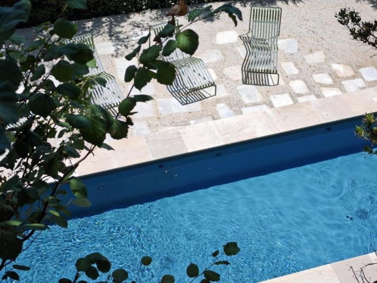 Piscina exterior de agua cristalina con tumbonas de jardín en Les Hauts de Sancerre