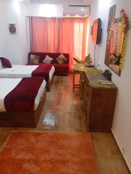 Habitación doble con decoración en rojo y dos camas en el Resort Florenza, suelo de madera y sofá