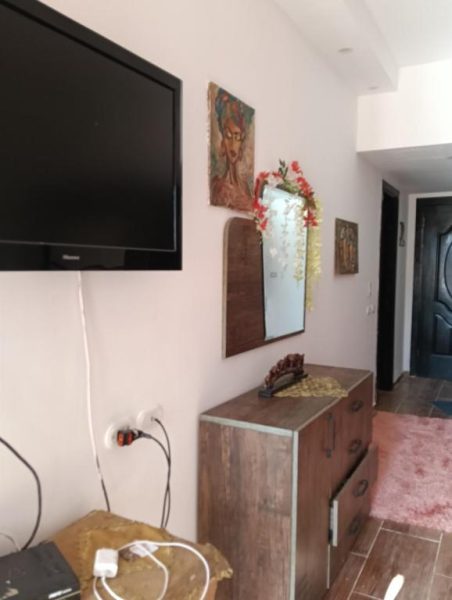 Habitación del Resort Florenza con televisión Hisense, cómoda de madera y espejo decorativo con flores