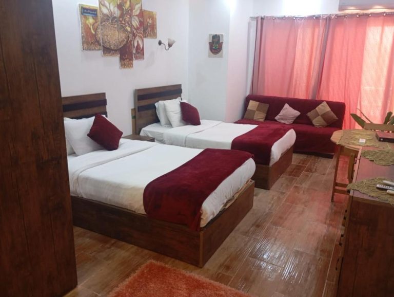 Habitación doble con dos camas individuales y sofá rojo en el منتجع فلورينزا