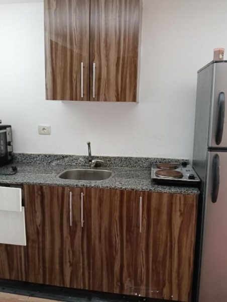 Cocina equipada con gabinetes de madera, fregadero y encimera de granito en منتجع فلورينزا
