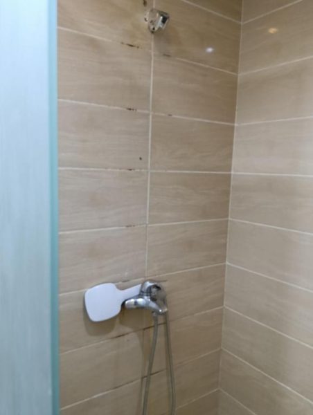 Ducha moderna con mampara de vidrio y azulejos beige en habitación del Resort Florenza