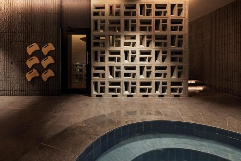 Zona de spa con piscina interior y decorativa pared de bloques de cemento en South Gate Hotel Okinawa Naha
