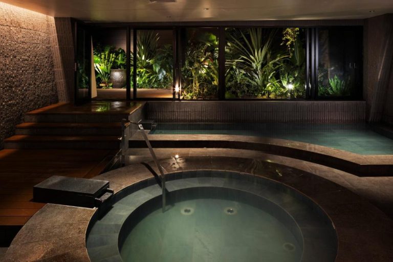 Jacuzzi y piscina interior con jardín tropical iluminado en South Gate Hotel Okinawa Naha