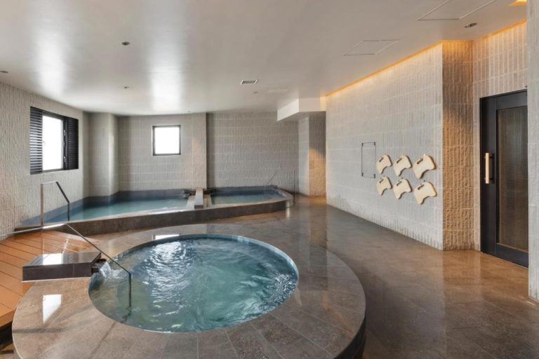 Zona de spa con jacuzzi circular y piscina interior del South Gate Hotel Okinawa Naha Tomari Port