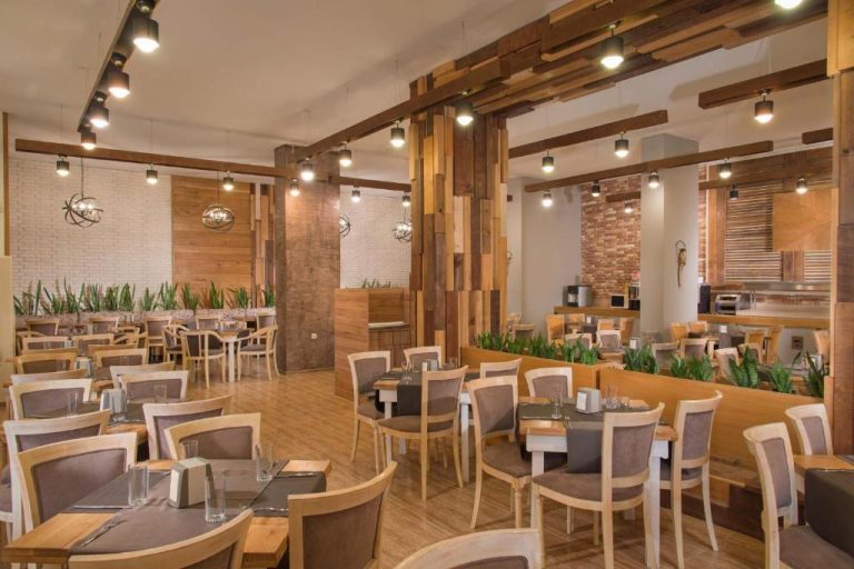 Restaurante interior con mesas elegantes y decoración en madera del Hotel Alba All Inclusive