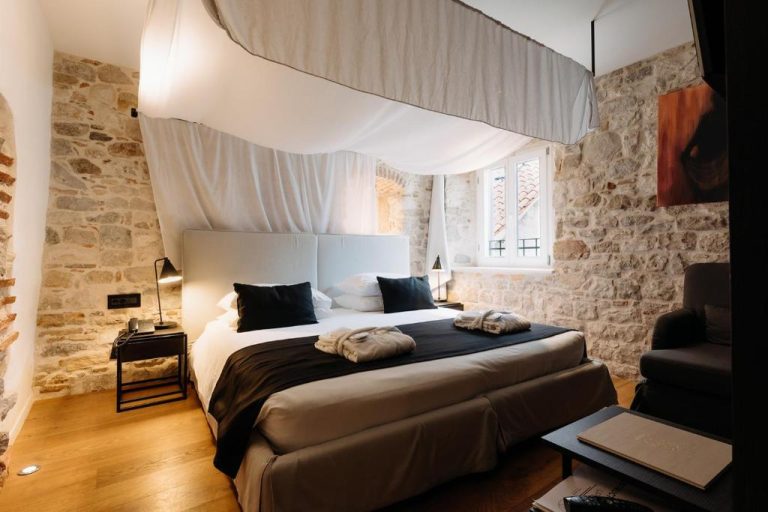 Habitación con cama dosel y paredes de piedra vista en el Murum Heritage Hotel