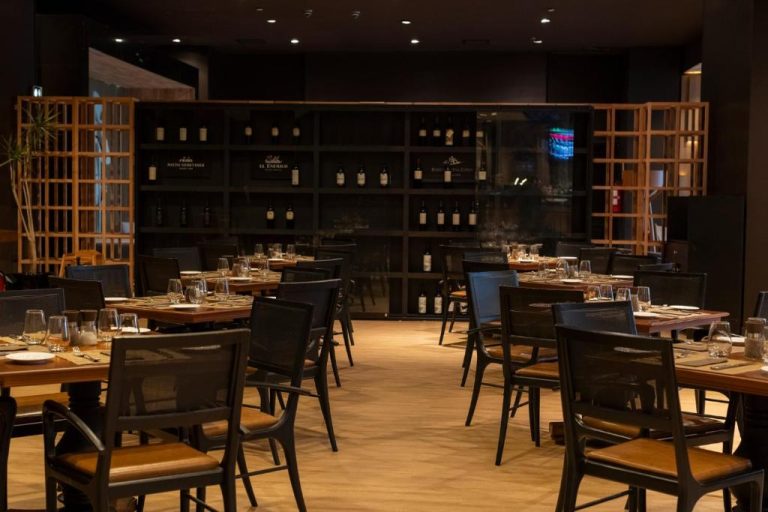 Restaurante elegante con bodega de vinos y mesas preparadas para cenar en el hotel Enjoy Punta del Este