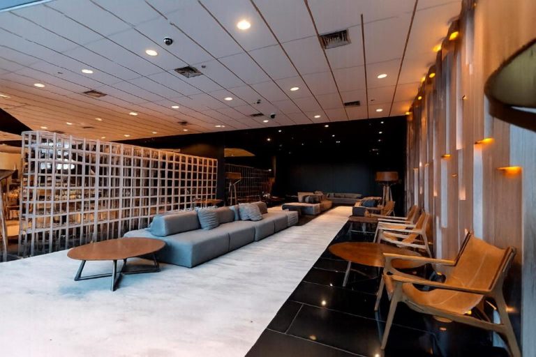 Elegante sala lounge con sofás grises y sillones de madera en el hotel Enjoy Punta del Este