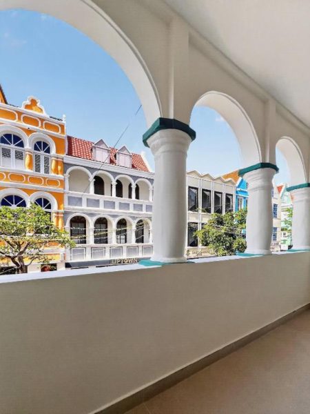 Terraza con arcos y columnas del Majestic City Palace Hotel con vistas a edificios coloniales coloridos