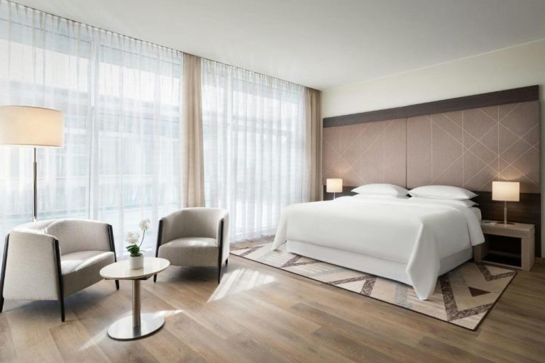 Habitación doble deluxe con cama king size y ventanales luminosos en Sheraton Milan Malpensa Airport Hotel