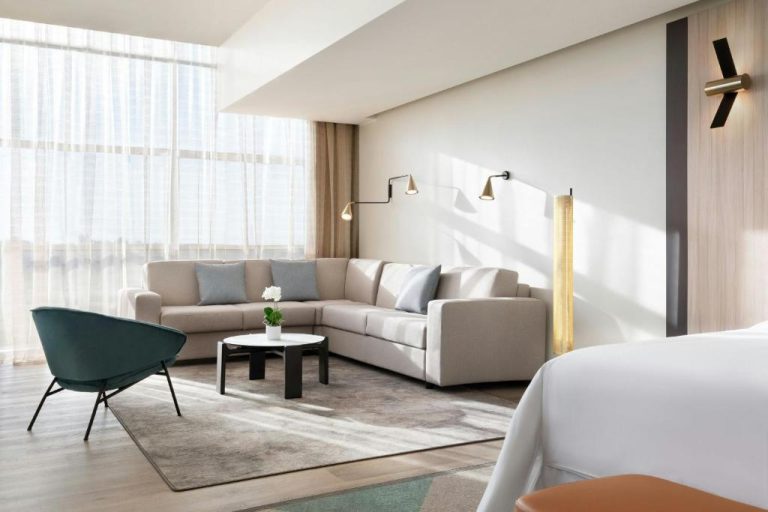 Amplio salón de suite con sofá rinconera y sillón verde en Sheraton Milan Malpensa Airport Hotel