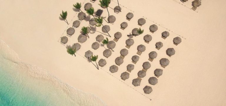 Vista aérea de la playa con sombrillas de palma y tumbonas del Paradisus Grand Cana en Punta Cana