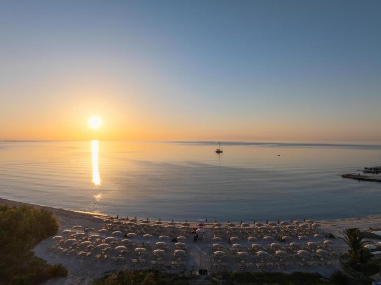 Vista aérea de la playa con sombrillas y tumbonas al atardecer en AMASEA Resort