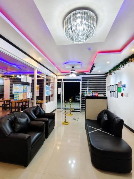 Lobby con sofás de cuero negro e iluminación LED de colores en Marias Hotel