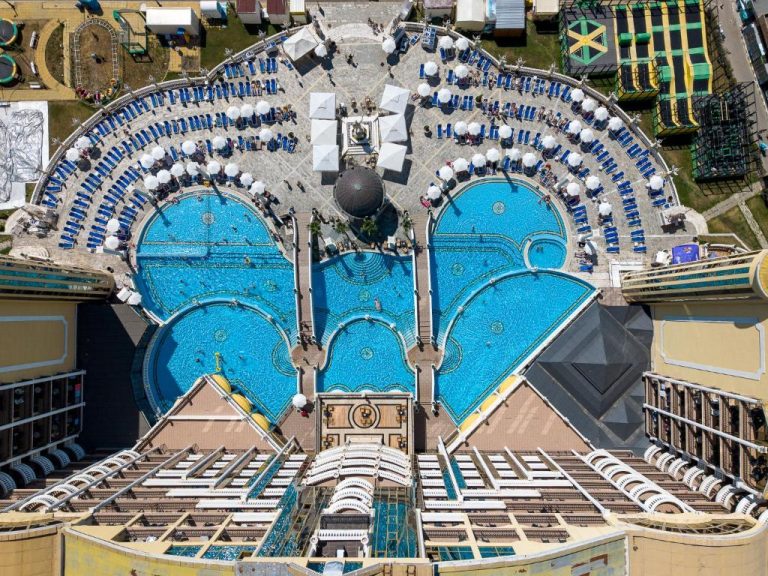 Vista aérea de las piscinas exteriores del Imperial Palace Hotel con tumbonas y sombrillas azules