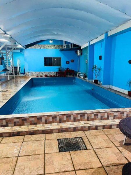 Piscina interior cubierta con techo abovedado y paredes azules del Hostal Pequeña Habana