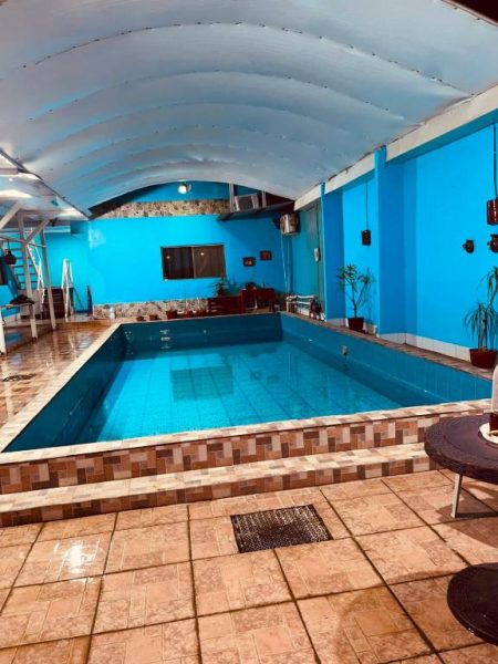 Piscina interior climatizada del Hostal Pequeña Habana con paredes azules y techo abovedado blanco