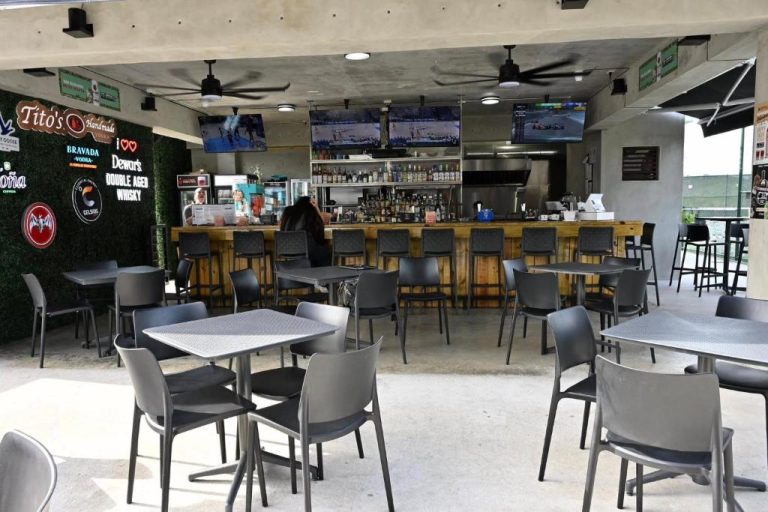 Bar y terraza interior con mesas y pantallas de televisión en Hacienda del Sur