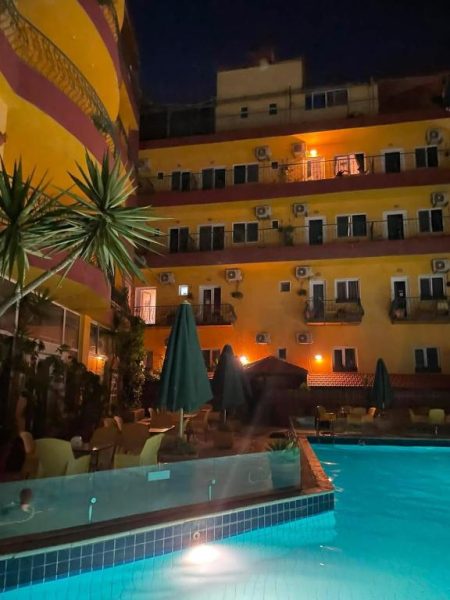 Piscina exterior iluminada del Mariam Hotel durante la noche con tumbonas y sombrillas