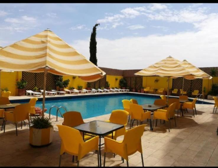 Terraza exterior con piscina, sombrillas y sillas amarillas del Mariam Hotel