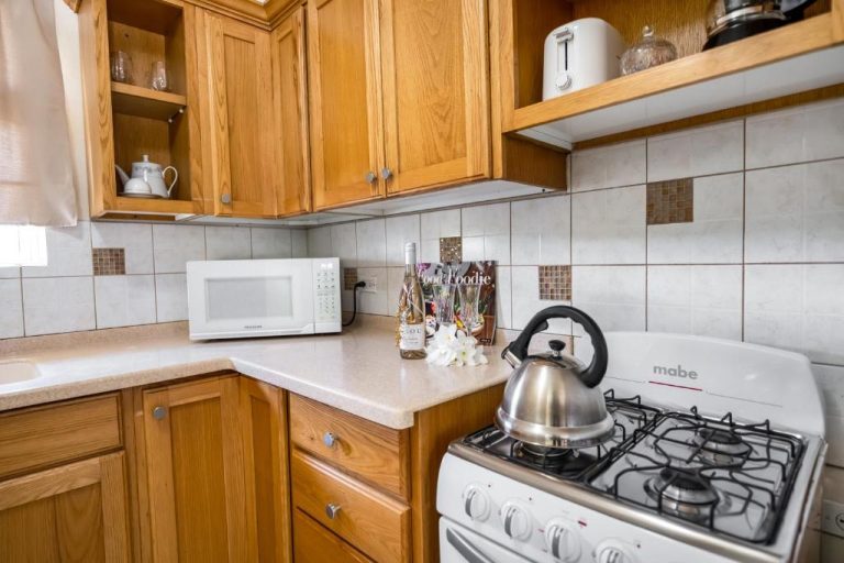 Cocina equipada con estufa de gas, microondas y armarios de madera en Adulo Apartments
