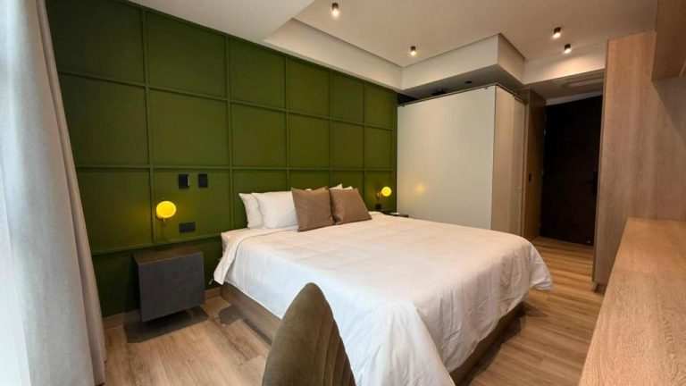 Habitación doble con pared verde y cama king size en Autenthico Atempo Local Suites Medellín